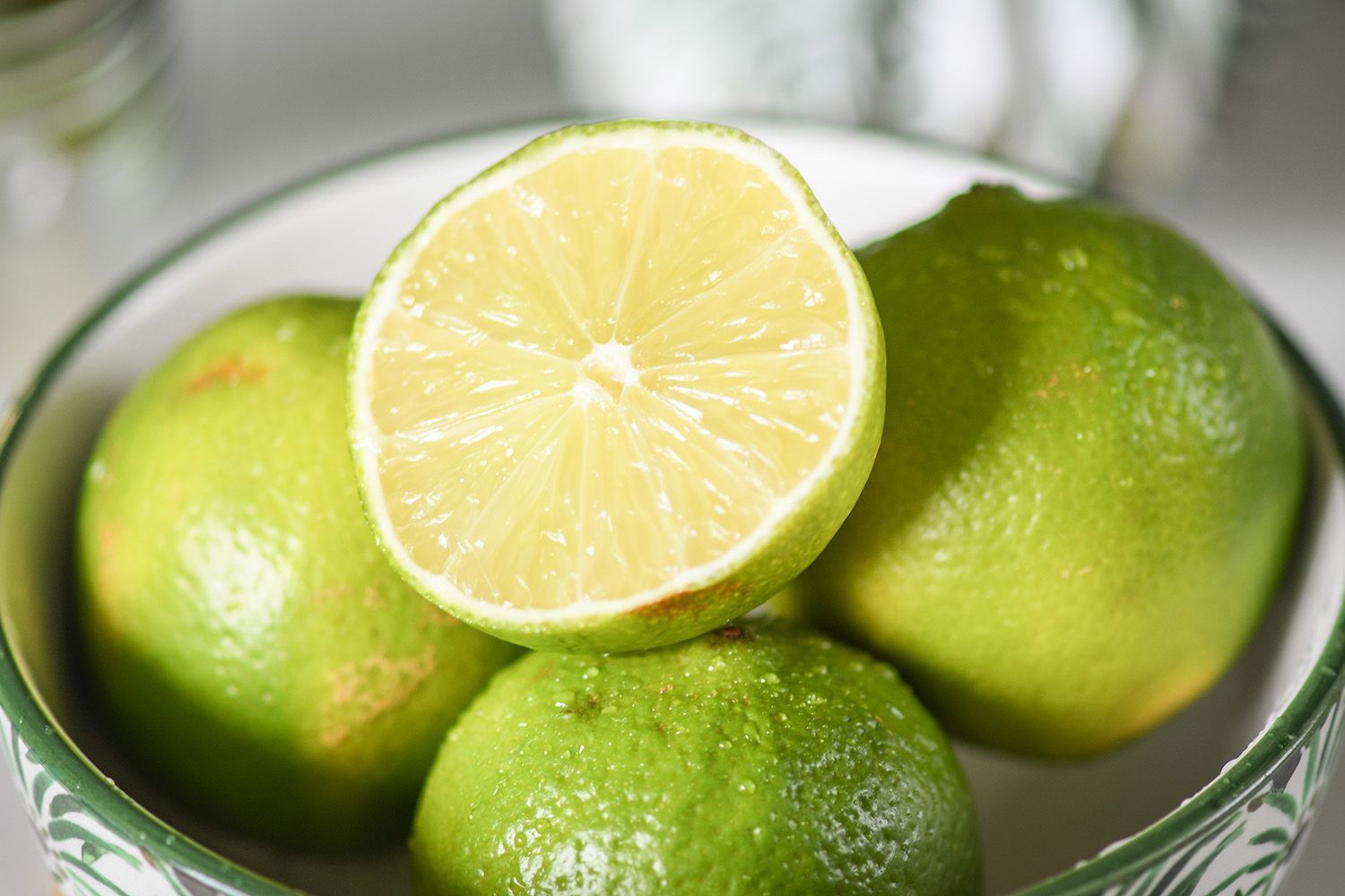 Citron vert entier posé à côté d'un demi citron vert coupé, pulpe juteuse et zeste visibles